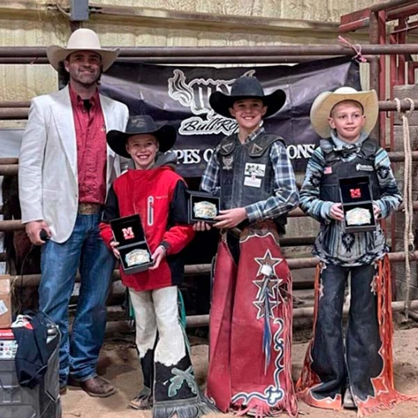 Rodeos and Bucaroos Gallery A group of boys donning cowboy hats and shirts hold up their award custom belt buckles with pride.